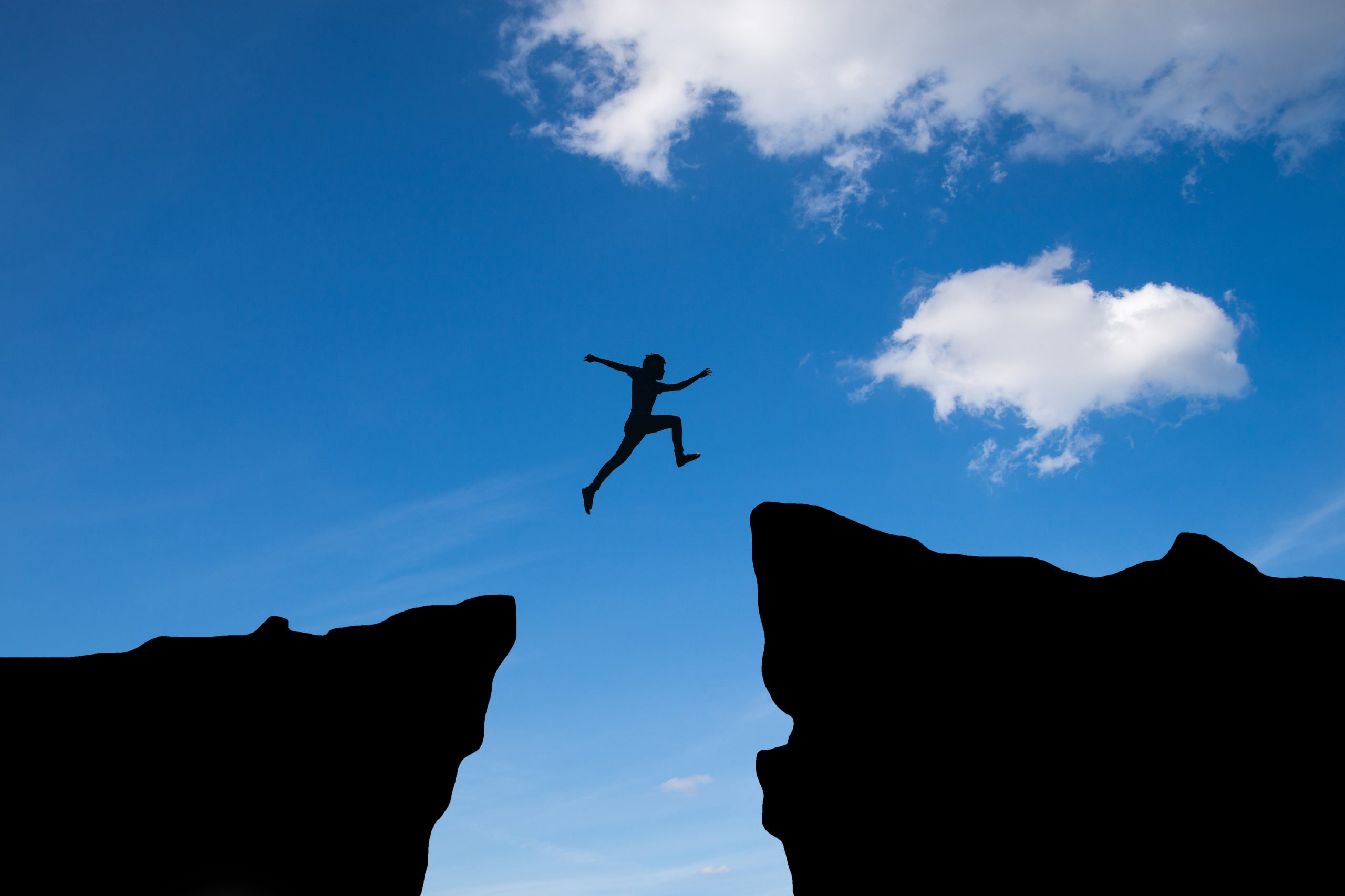 Man jump through the gap between hill.man jumping over cliff on
